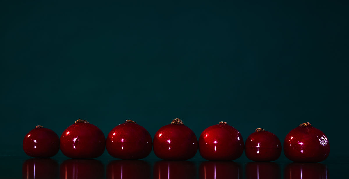 Bordeauxrøde julekugler på mørk baggrund – vin som julegave fra Vin & Mer